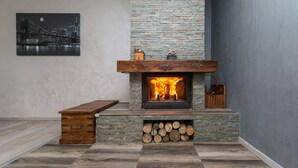 A fireplace with a stone facade, a wooden mantel, and a bench to the left. - Holiday House Papuk is Located in Park of Nature (Brestovac)