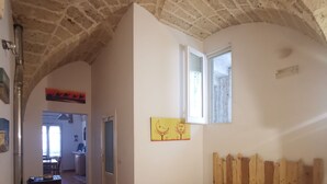 Un dormitorio con cabecera de madera, cama con colcha color beige, una ventana y un cuadro en la pared.