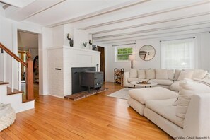 Relax in this inviting living room with a fireplace, comfortable sofa, and wooden staircase.