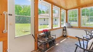 A sunroom with large windows, a wooden ceiling, and a seating area with a table and chairs. - Charming 3 bedroom, 2 bathroom Catskills cottage (Saugerties)