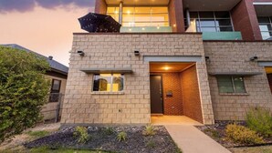 A modern two-story house with a brick facade, a large window on the upper floor, and a visible door on the ground floor. - Eclectic 3-Story Townhouse - Central Location! (Fort Worth)