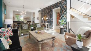 A spacious living area with a sofa, a coffee table, and a dining area in the background. - Eclectic 3-Story Townhouse - Central Location! (Fort Worth)