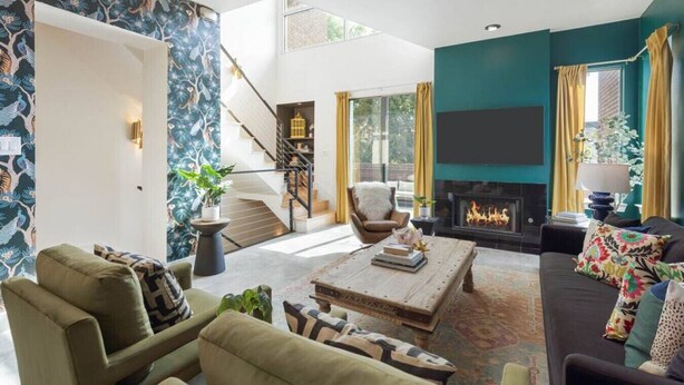 A spacious living room with a fireplace, comfortable seating, and a staircase leading to an upper level. - Eclectic 3-Story Townhouse - Central Location! (Fort Worth)