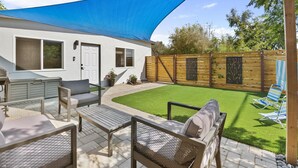 Ein Patio mit Gartenmöbeln, einem Grill und einem Holzzaun.