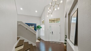 A staircase leading to a second floor with a modern light fixture above.