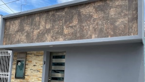 Un edificio con fachada de piedra, una puerta de metal y un acceso con ventanal.