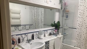Un baño con lavamanos blanco, un espejo, un inodoro y zona de ducha.