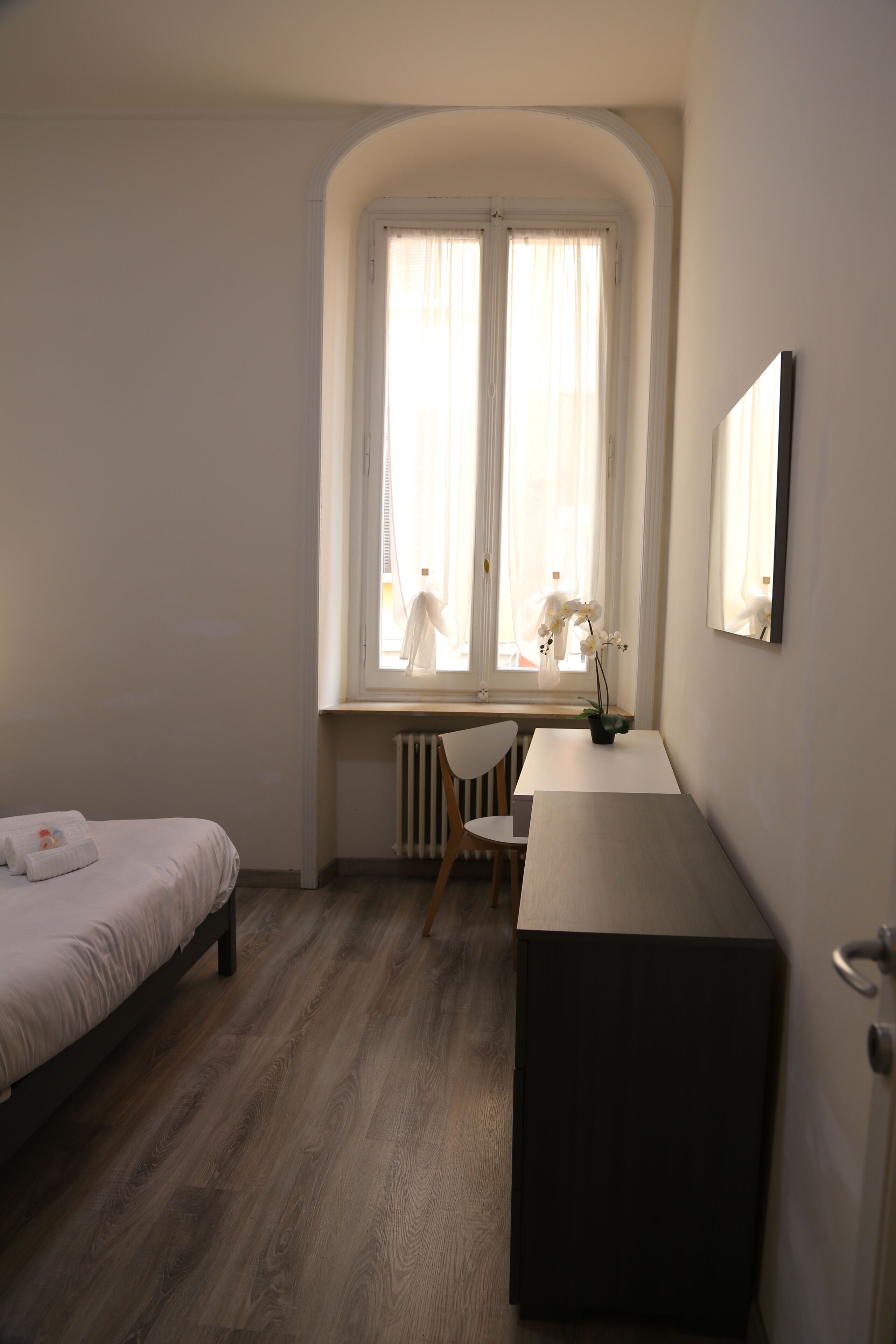 Ein Schlafzimmer mit Bett, Schreibtisch, Stuhl und Heizkörper.