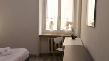Ein Schlafzimmer mit Bett, Schreibtisch, Stuhl und Heizkörper.