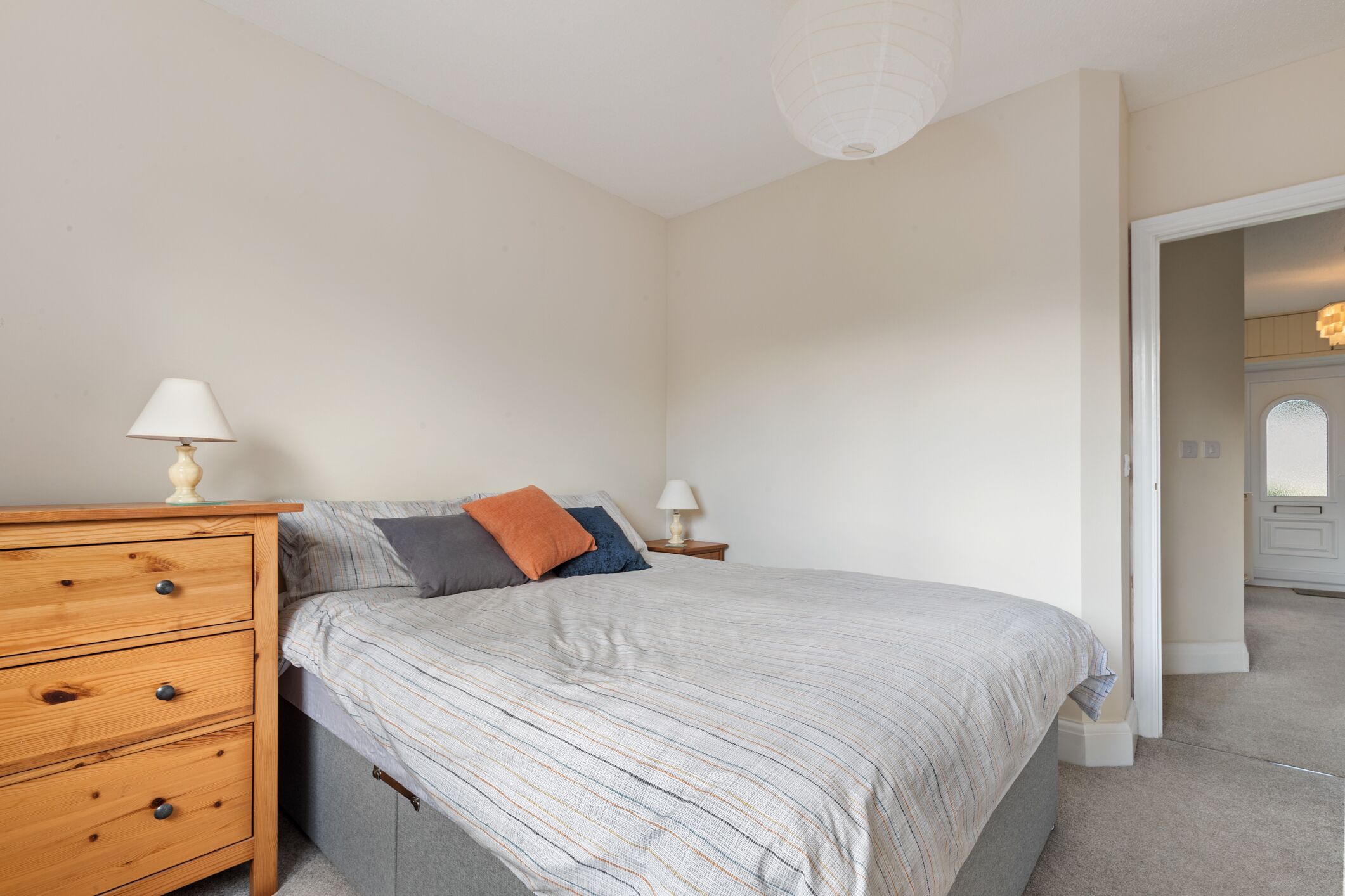 A bedroom with a bed, a wooden dresser, and two bedside tables with lamps.