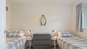 A bedroom with two beds, a dresser, bedside lamps, and a mirror on the wall. - Ballyroan - Peaceful, Dog Friendly Cottage (Tenby)