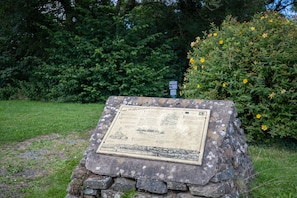 Un monument en pierre avec une plaque d’information, situé dans un parc.