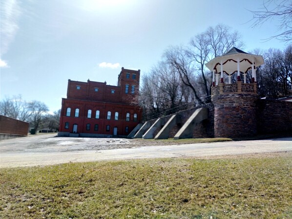 A red brick building with a tower, a stone wall, and a gazebo. - Stay in the Old Hauenstein Brewery on the 1st level (New Ulm)