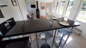 A modern kitchen with a central island, bar stools, and a dining area with a table and chairs. - Completely renovated cottages between Honfleur and Pont Audemer (Saint-Pierre-du-Val)