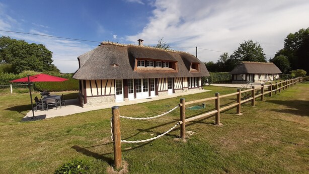 A traditional half-timbered house with a thatched roof, a wooden fence, and a red umbrella in the foreground. - Completely renovated cottages between Honfleur and Pont Audemer (Saint-Pierre-du-Val)