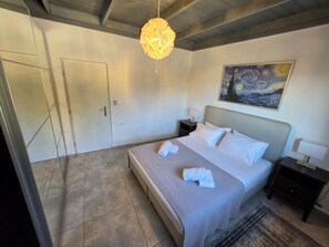 Un dormitorio con una cama, un cuadro, una lámpara colgante y una puerta.