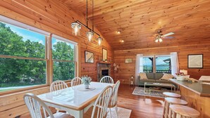 A wooden cabin interior with a dining table, chairs, a sofa, and a bar area. - This Beautiful Cabin with Mountain views is the Perfect getaway! (Townsend)