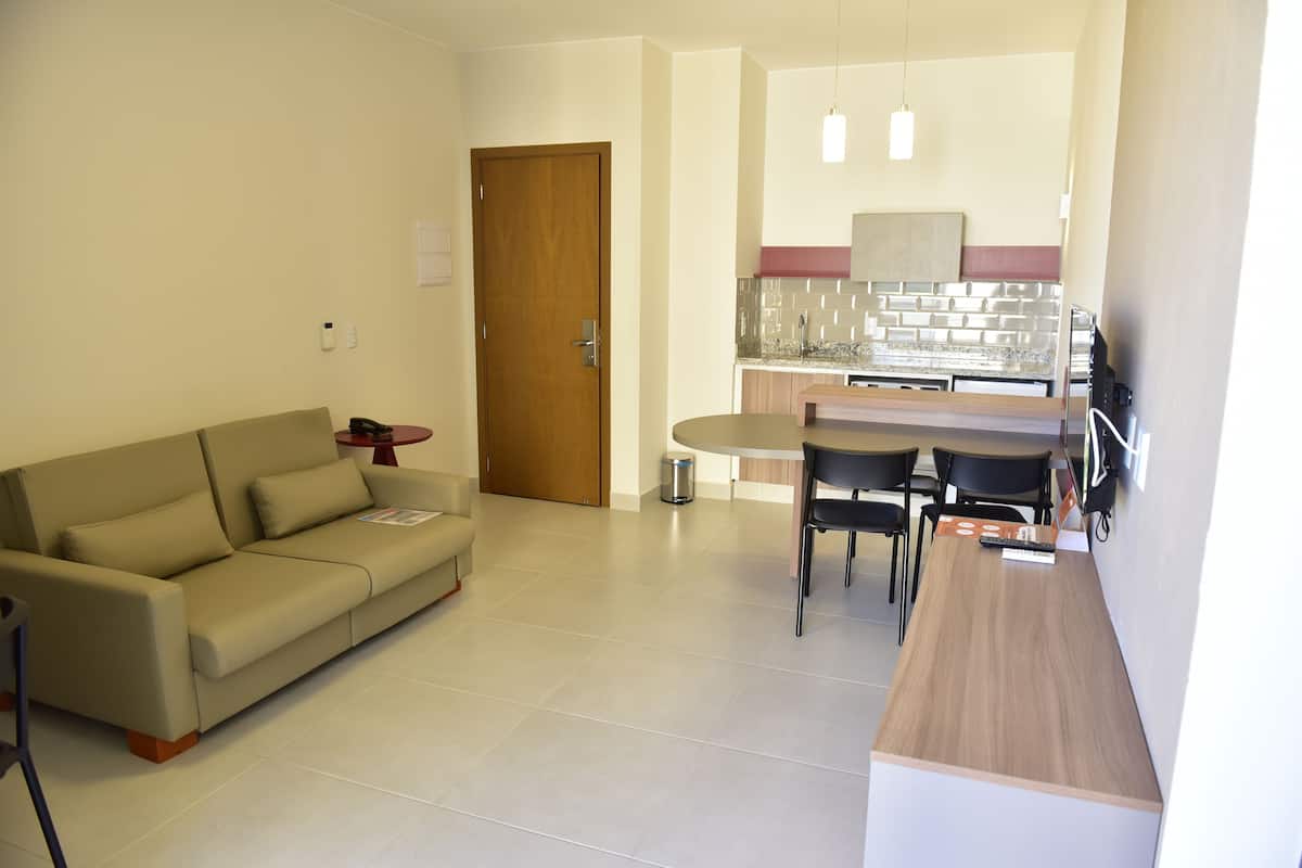 Una sala de estar moderna con un sofá, una mesa de comedor con sillas, una zona de cocina con mostrador y luces colgantes.