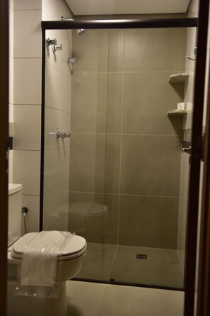 Eine Duschkabine mit Glaswänden und eine Toilette links daneben.