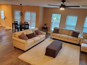 Relax in this inviting living room with a large sofa, matching ottoman, and dining area.