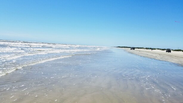 Uma praia com areal arenoso e céu limpo.