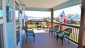Um deck coberto ao ar livre com móveis de vime e uma bandeira do Texas.