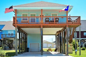 A two-story building with a balcony, a garage, and a small garden area.