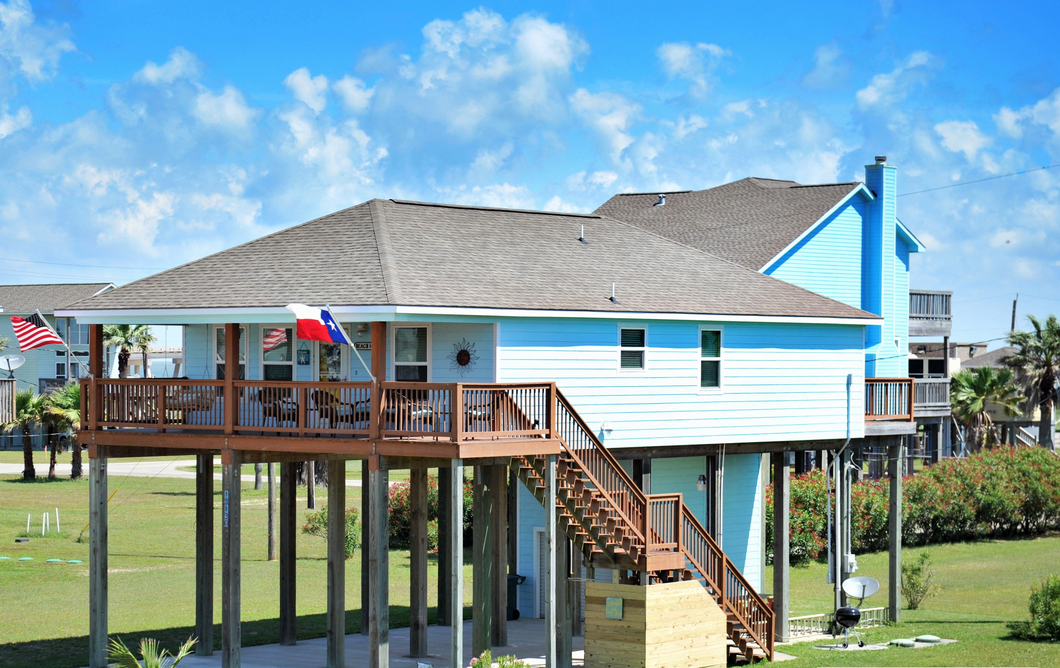 Ett tvåvåningshus med en träveranda och en balkong, som stöds av träpelare.