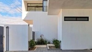 Een modern gebouw met een plat dak, een kleine tuin en een geplaveid binnenterrein.