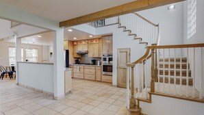Une cuisine spacieuse dotée de meubles en bois, d’un îlot central et d’un escalier menant à l’étage supérieur.