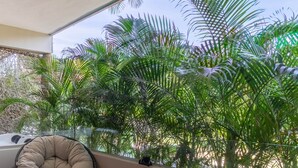 A modern room with a large window overlooking a lush garden, a comfortable chair, a small table with a cup, and a bathtub visible through the window. - TULUM XAMIRA PRIVATE SPA  BALCONY (tulum)