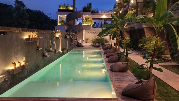 A serene indoor swimming pool with a wooden deck, surrounded by potted plants and seating areas. - TULUM XAMIRA PRIVATE SPA  BALCONY (tulum)