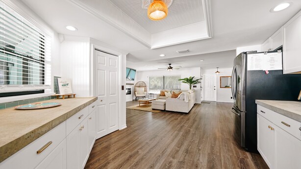 A spacious kitchen with white cabinetry, a wooden countertop, and a black refrigerator.
