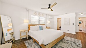 A modern bedroom with a wooden bed, bedside tables, a ceiling fan, and a patterned rug.