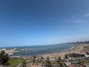 A coastal cityscape with a beach, marina, and urban buildings.