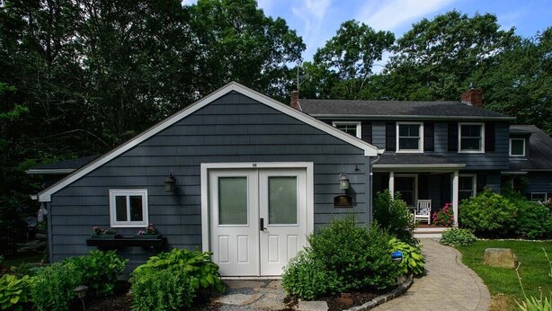 A two-story house with a dark gray exterior, a front porch, and a well-maintained garden.