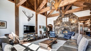 A spacious living room with a stone fireplace, leather sofas, and a television.