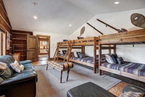 A cozy room with bunk beds, a leather couch, and a wooden ladder.