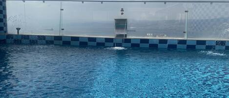 Una piscina con borde a cuadros y barandilla de vidrio.