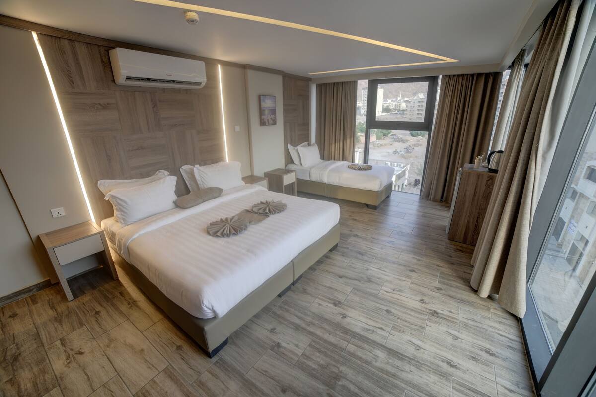 A modern hotel room with a large bed, a smaller bed, and a balcony with curtains.