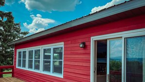 Un edificio rojo con terraza de madera y puerta corrediza de vidrio.