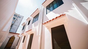 A narrow street with white buildings, a visible exit sign, and a door with a metal gate. - CS4- Impressive Colonial 1BR Apartment w/Private Parking & Open Spaces (San Juan)