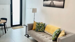 A living room with a sofa, a dining table, and a lamp. - CS4- Impressive Colonial 1BR Apartment w/Private Parking & Open Spaces (San Juan)