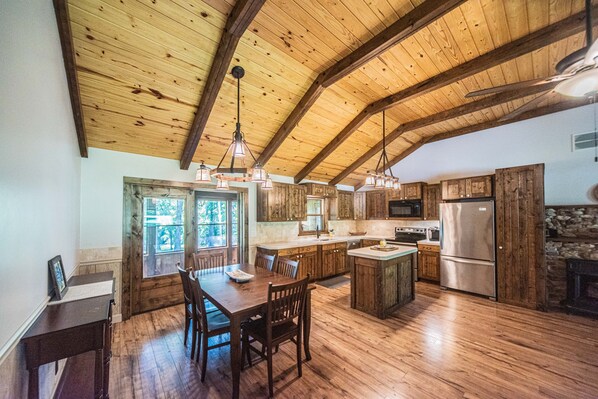 Una cocina amplia con vigas de madera, un comedor y una chimenea de piedra.