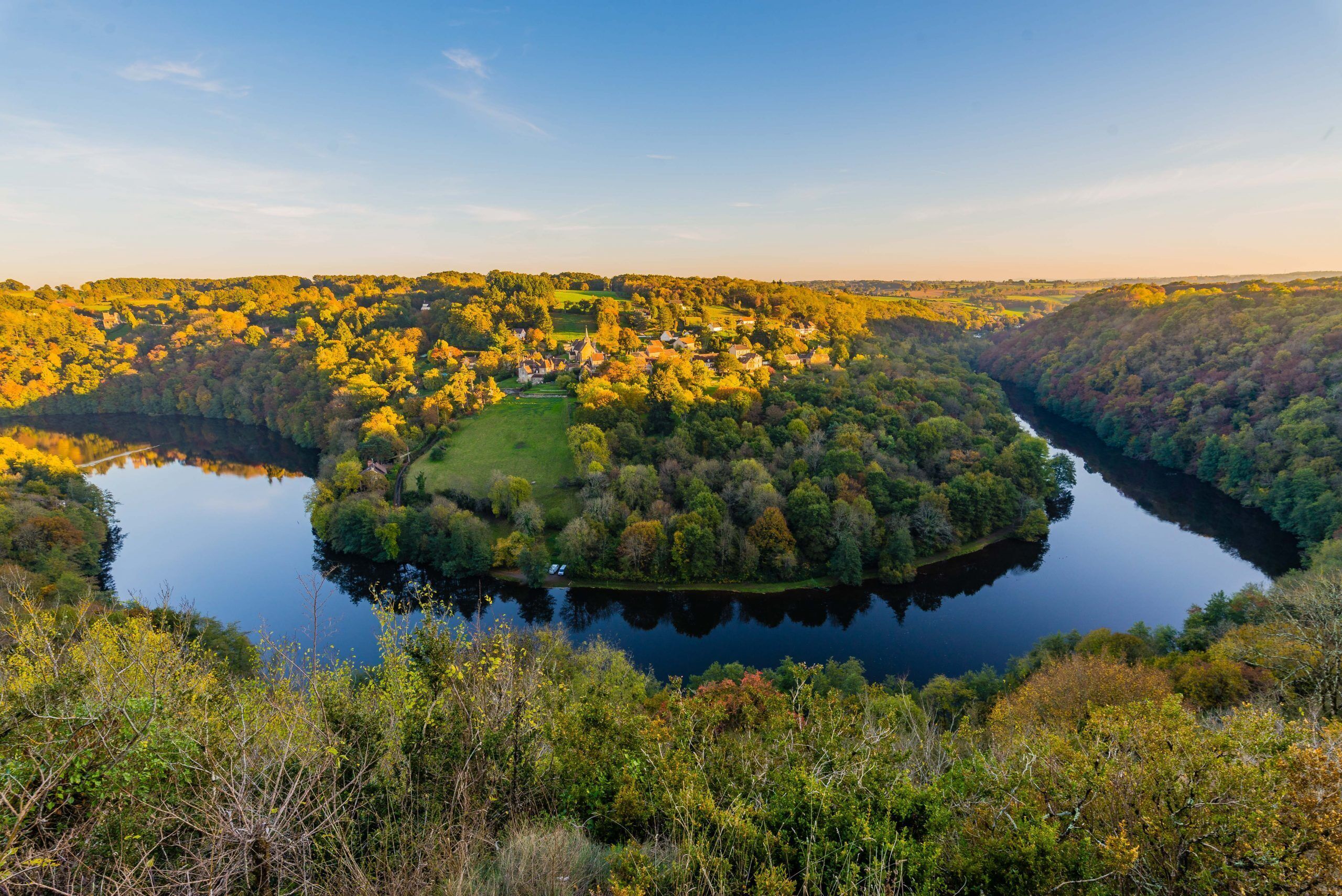 Un pueblo a orillas del lago rodeado de un bosque denso.
