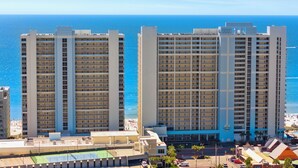 A high-rise hotel with multiple floors, a pool area, and a view of the ocean. - Spacious Corner Unit! Oceanfront! Majestic! Pools! (Panama City Beach)