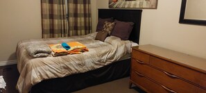 Cozy bedroom with a bed, dresser, and window.