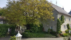 A courtyard with a large tree, a white lantern, and a bench. - Vacation apartment "Haus Herzblick" directly on the pilgrimage path "Herzweg des Friedens" in Ts. (Berghausen)