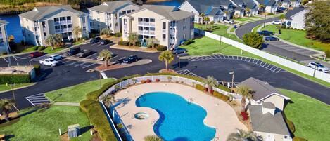 A residential area with a swimming pool, multiple apartment buildings, and a parking lot.