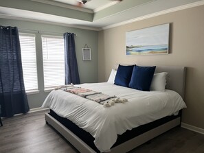Relax in this serene bedroom with a large bed, decorative throw blanket, and a beautiful landscape painting above.